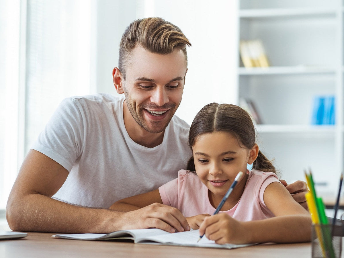 A father and his daughter writing together at a desk