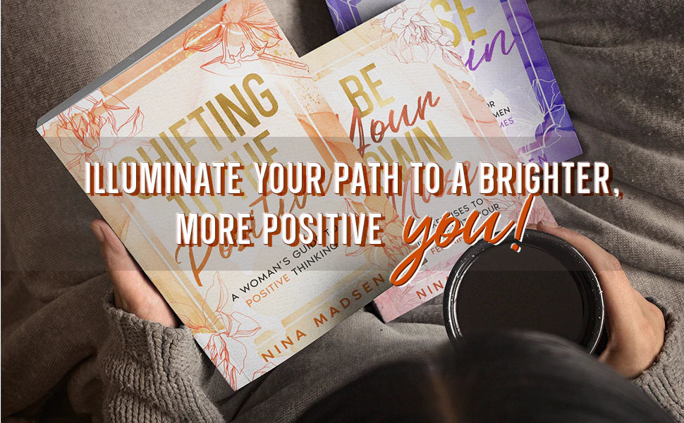 Shifting to the Positive, Be Your Own Muse and Rise Again by Nina Madsen held over a cozy blanket, next to a cup of coffee.