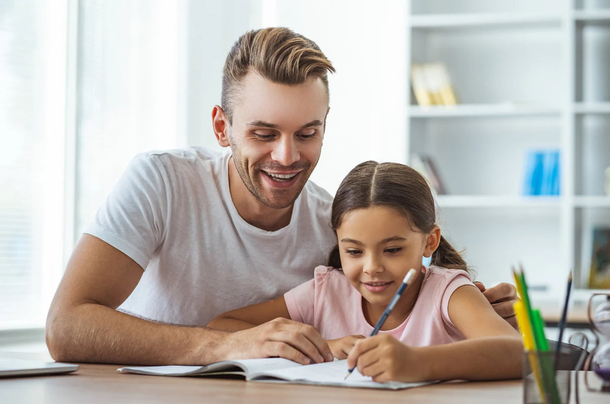 A dad and his daughter writing together at the table