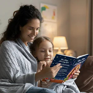 A mother and her daughter read You Shine, Amazing Girl together under a blanket.