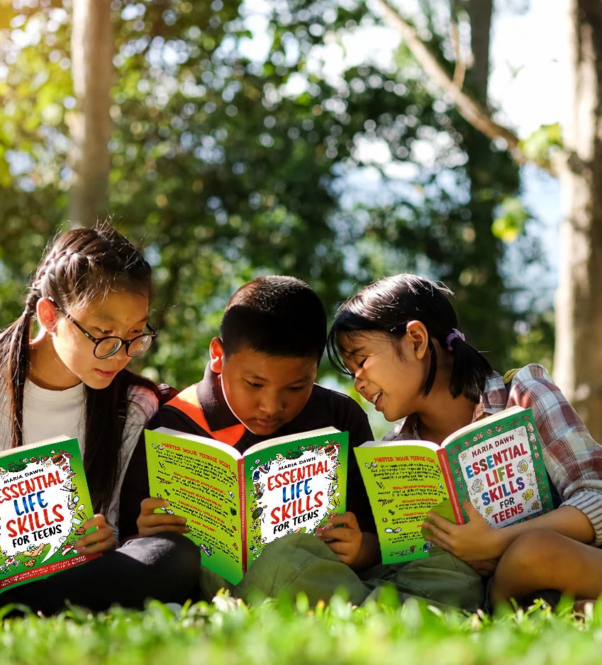 Three kids reading Essential Life Skills for Teens together on the grass