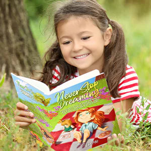 A smiling girl lies in the grass reading Never Stop Dreaming.