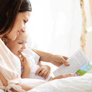 A mother and her daughter read Never Stop Dreaming in bed.