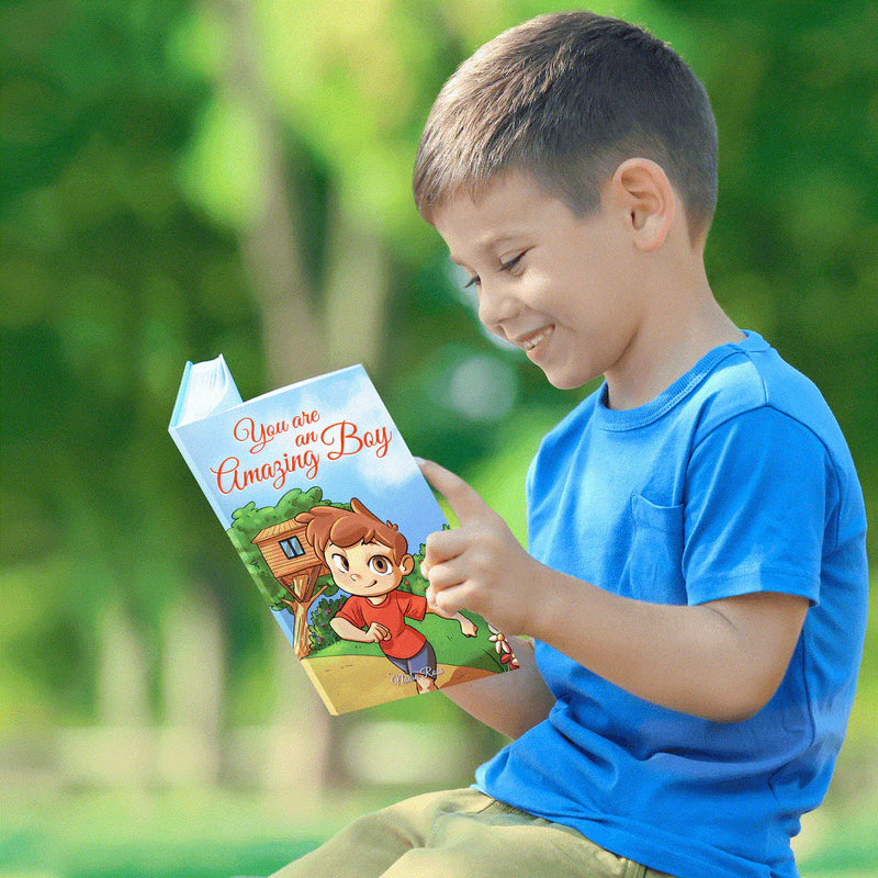 A smiling boy reads You Are an Amazing Boy outdoors.