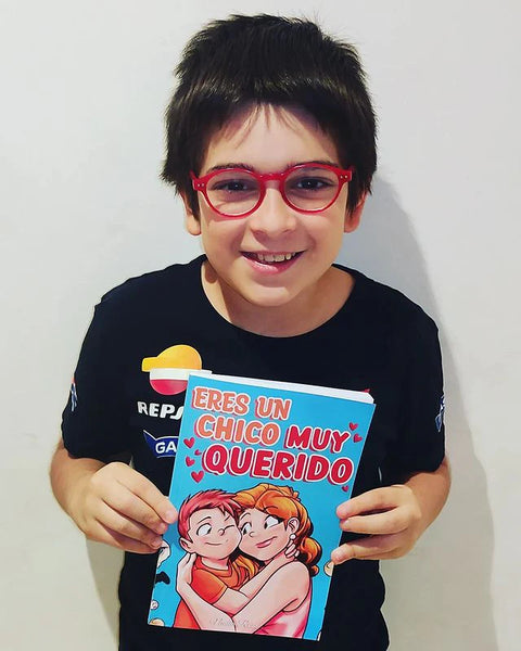 A boy holding the book Eres un chico muy querido